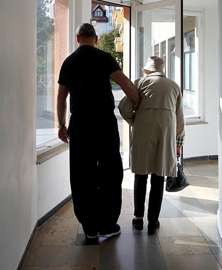 Pflegekraft begleitet eine Seniorin