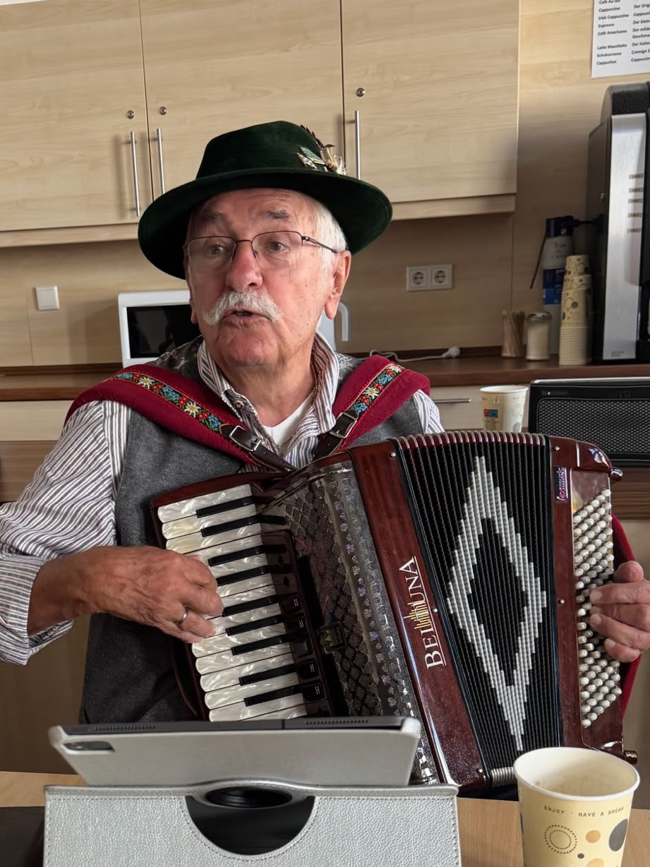 Musiker mit Trachtenhut und Akkordeon beim Spielen in der Wohnküche