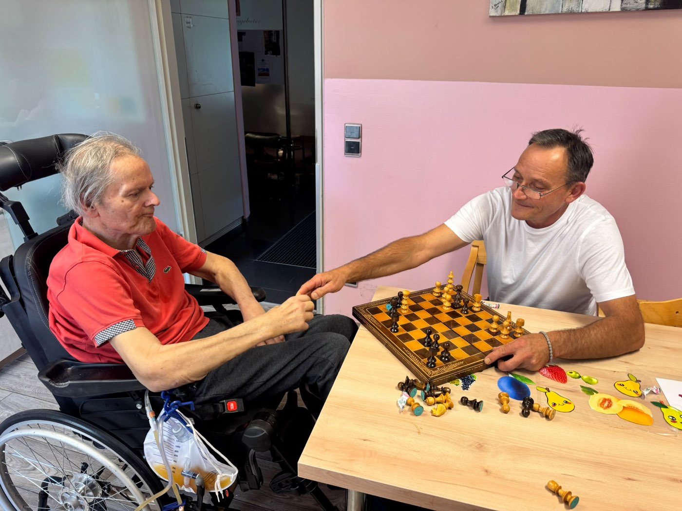 Ein Betreuer und ein Tagesgast im Rollstuhl beim Schachspiel am Tisch